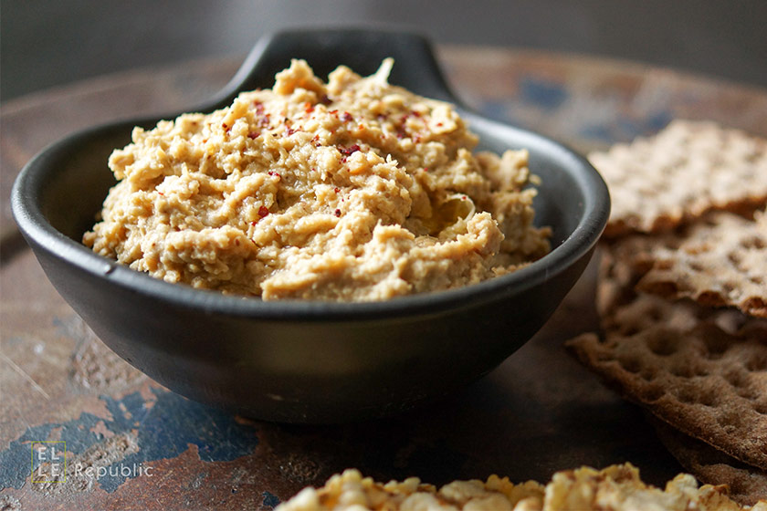 Hummus mit Sumach, Tahini, Zitronensaft, Cayenne-Pfeffer, Kichererbsen in schwarzer Schüssel