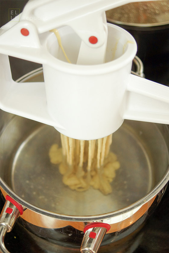 Spätzleteig durch Spätzlepresse drücken für schwäbische Spätzle selbstgemacht