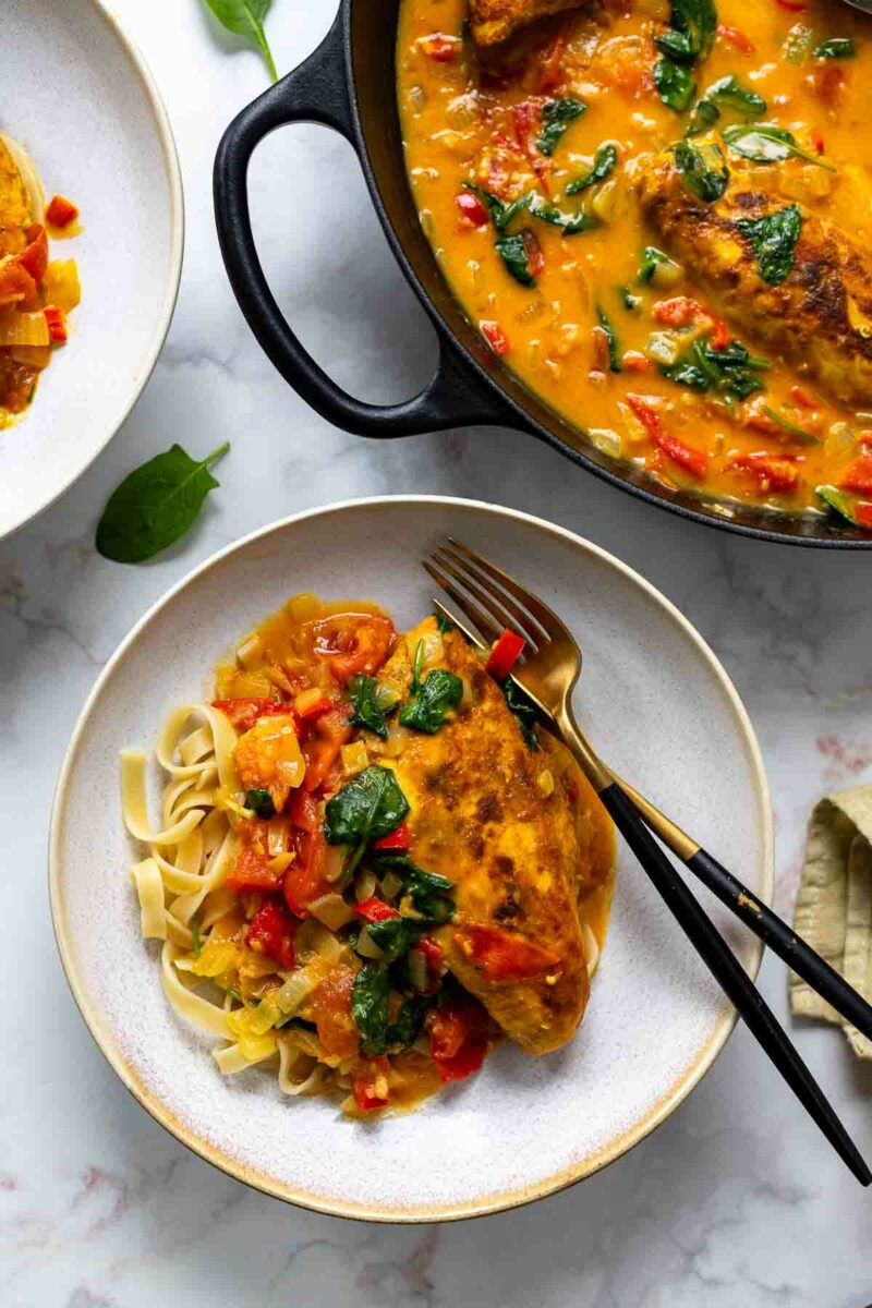 Hähnchen-Curry Rezept mit Kokos, Spinat und Tomaten serviert mit Nudeln