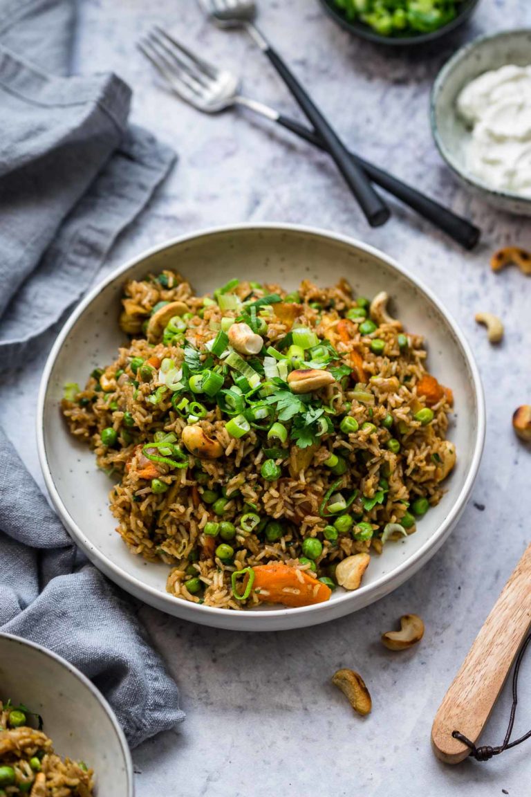 Curry Reis Rezept mit Gemüse – Farbiger Curry-Reis mit knackigem Gemüse, garniert mit frischen Kräutern und Kashewkerne.