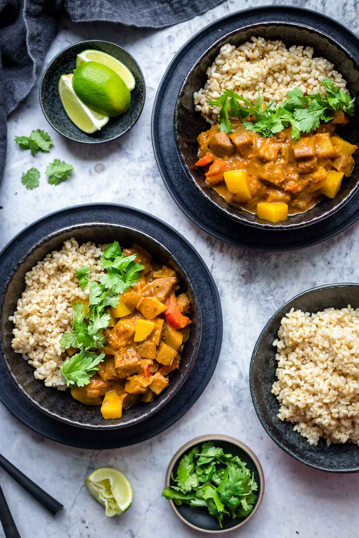 Aloo Baingan, Indisches Auberginen Kartoffel Curry mit Tomaten und Kokosmilch Rezept, serviert mit Vollkornreis, Koriander und Limetten