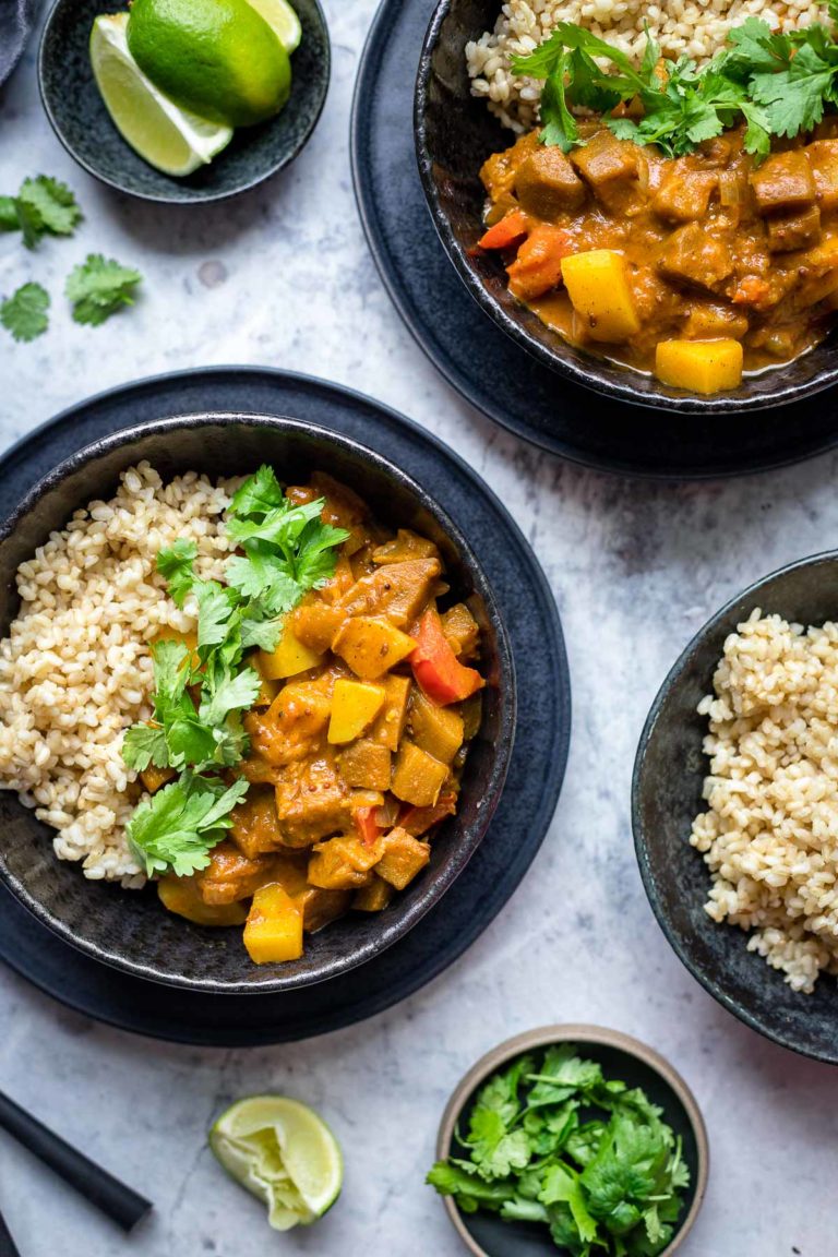 Indisches Auberginen Kartoffel Curry mit Tomaten und Kokosmilch Rezept, serviert mit Vollkornreis, Koriander und Limetten