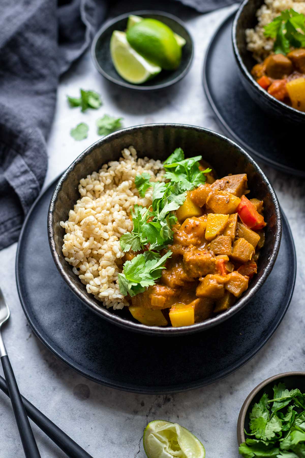 Indisches Auberginen Kartoffel Curry mit Tomaten und Kokosmilch Rezept, serviert mit Vollkornreis, Koriander und Limetten