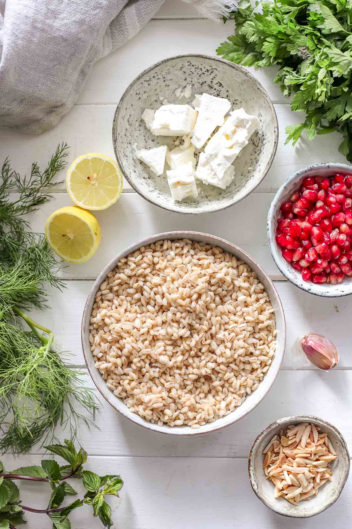 Zutaten für Gerstensalat mit Kräutern (Dill, Petersilie, Minze), Mandeln und Feta-Käse