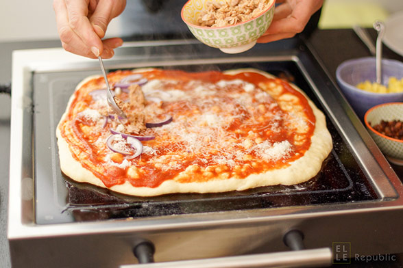 Selbstgemachte Grill-Pizza mit Thunfisch und Zwiebeln belegen