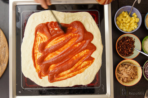 Für die Grill-Pizza den Pizzaboden mit passierten Tomaten bestreichen