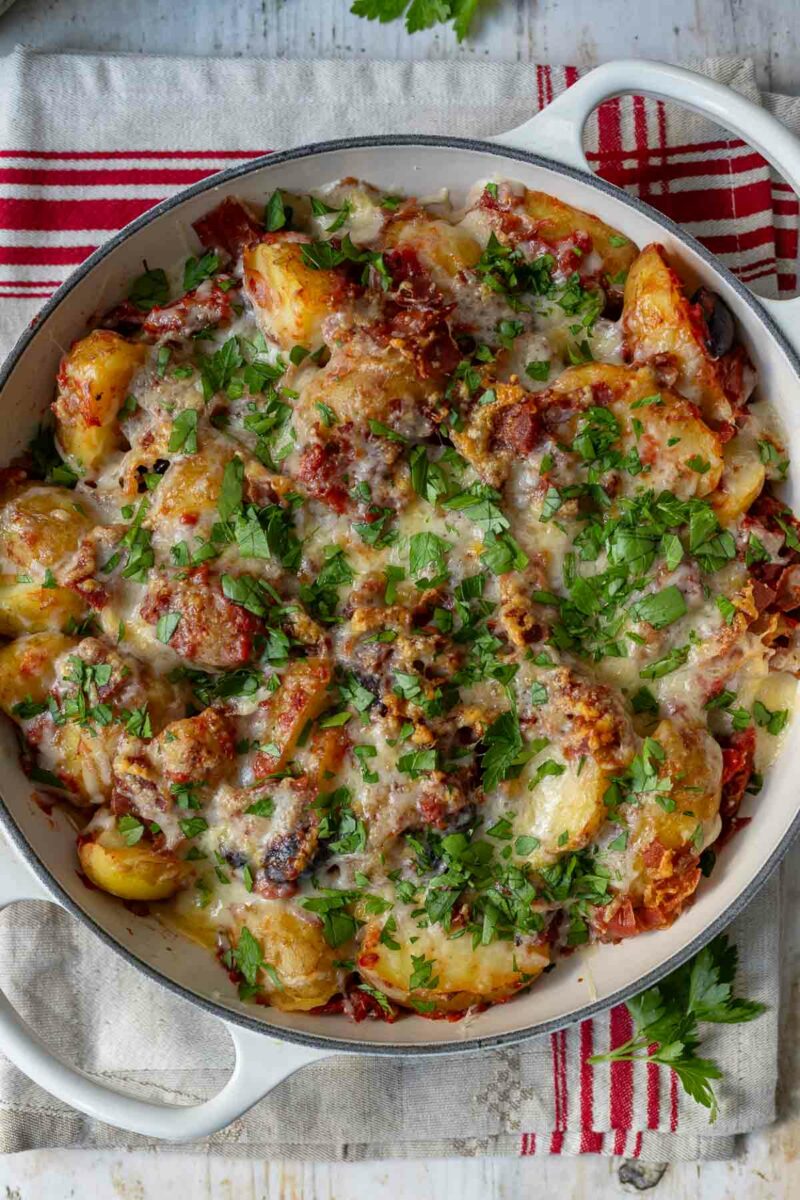 mediterraner Kartoffelauflauf mit jungen Kartoffeln, herzhaftem Parmaschinken, trockenen Tomaten, Kalamata Oliven und geschmolzenem Guyère-Käse.