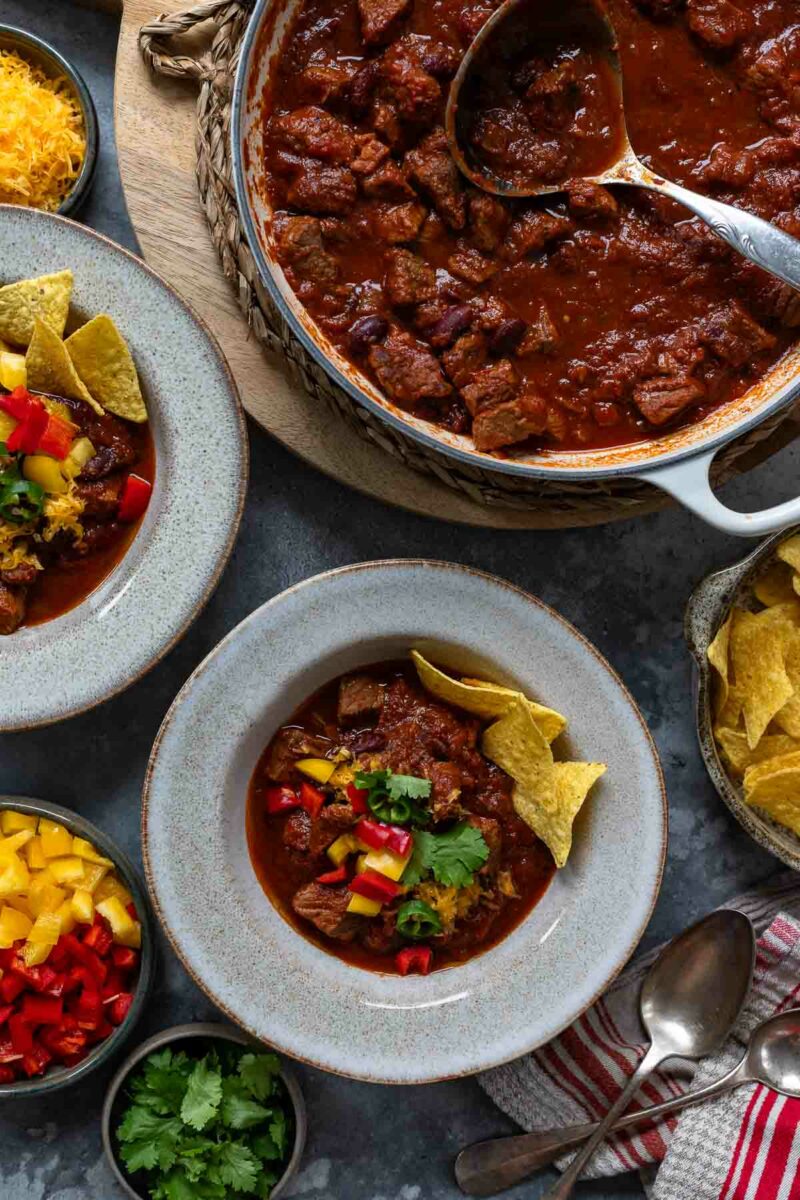 Chili con Carne mit Rindfleisch Rezept serviert mit Paprika, Cheddar-Käse und Tortilla Chips