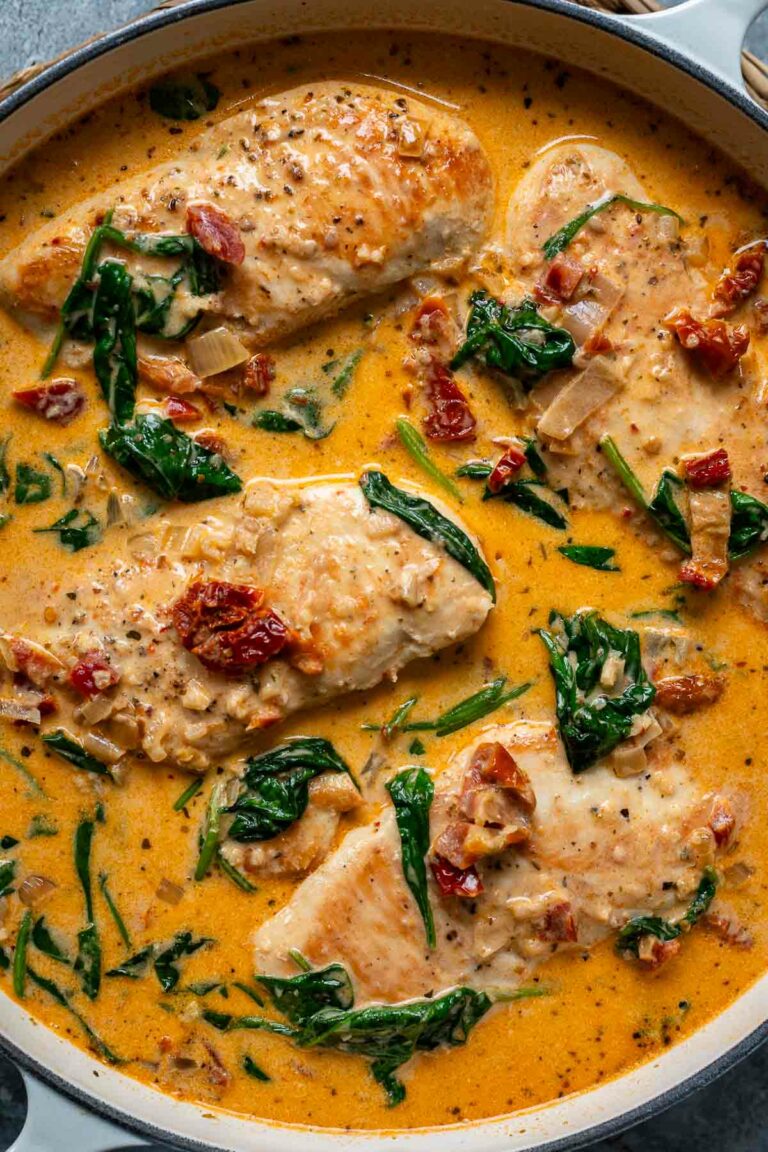 Nahaufnahme von Hähnchen in cremiger Parmesan-Sahnesoße mit getrockneten Tomaten und Spinat – ein einfaches, schnelles und köstliches Hähnchenfilet Rezept.