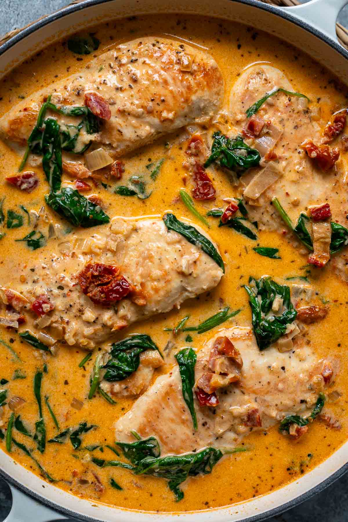 Nahaufnahme von Hähnchen in cremiger Parmesan-Sahnesoße mit getrockneten Tomaten und Spinat – ein einfaches, schnelles und köstliches Hähnchenfilet Rezept.
