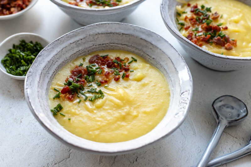 Kartoffel-Käse-Suppe Rezept mit Cheddar, Speck und Schnittlauch serviert in Schüsseln