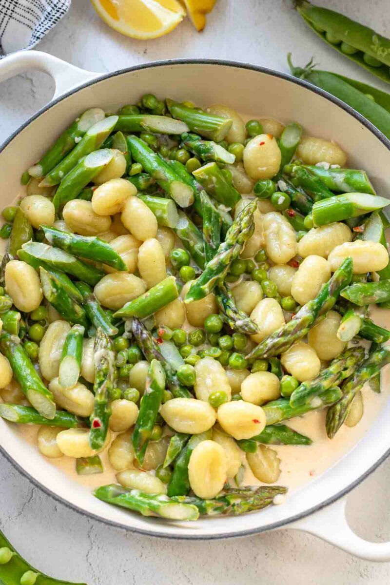 Gnocchi mit grünem Spargel und Erbsen in Sahnesoße in der Pfanne
