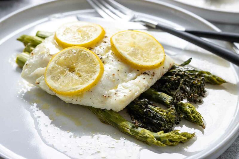 Kabeljau im Ofen Rezept mit Olivenöl und Zitronenscheiben serviert mit Spargel und Bimi (Brokkolini)