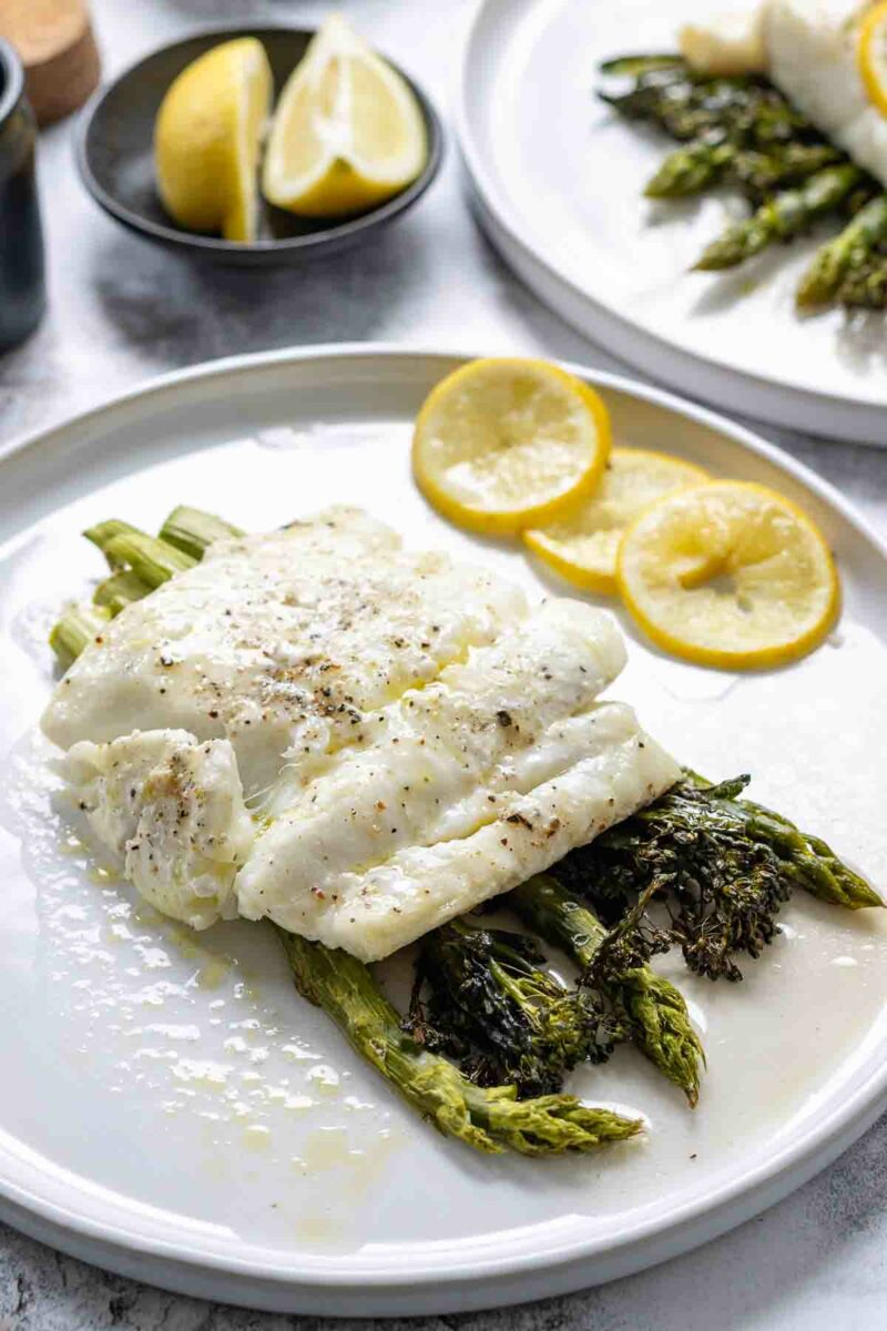 Kabeljau im Ofen Rezept mit Olivenöl und Zitronenscheiben serviert mit Spargel und Bimi (Brokkolini)