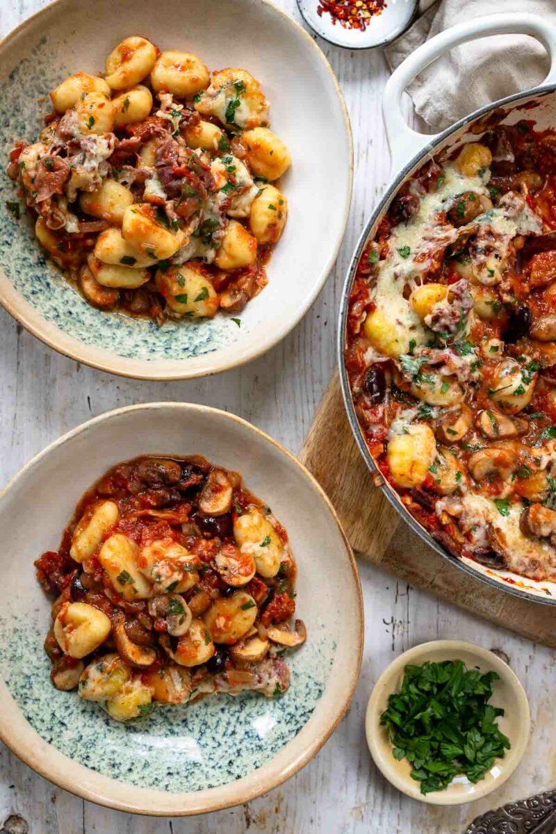 italienischer Gnocchi Auflauf mit Sardellen, Oliven, getrockneten Tomaten, Pilzen, Parmaschinken und Käse im Ofen gebacken und serviert